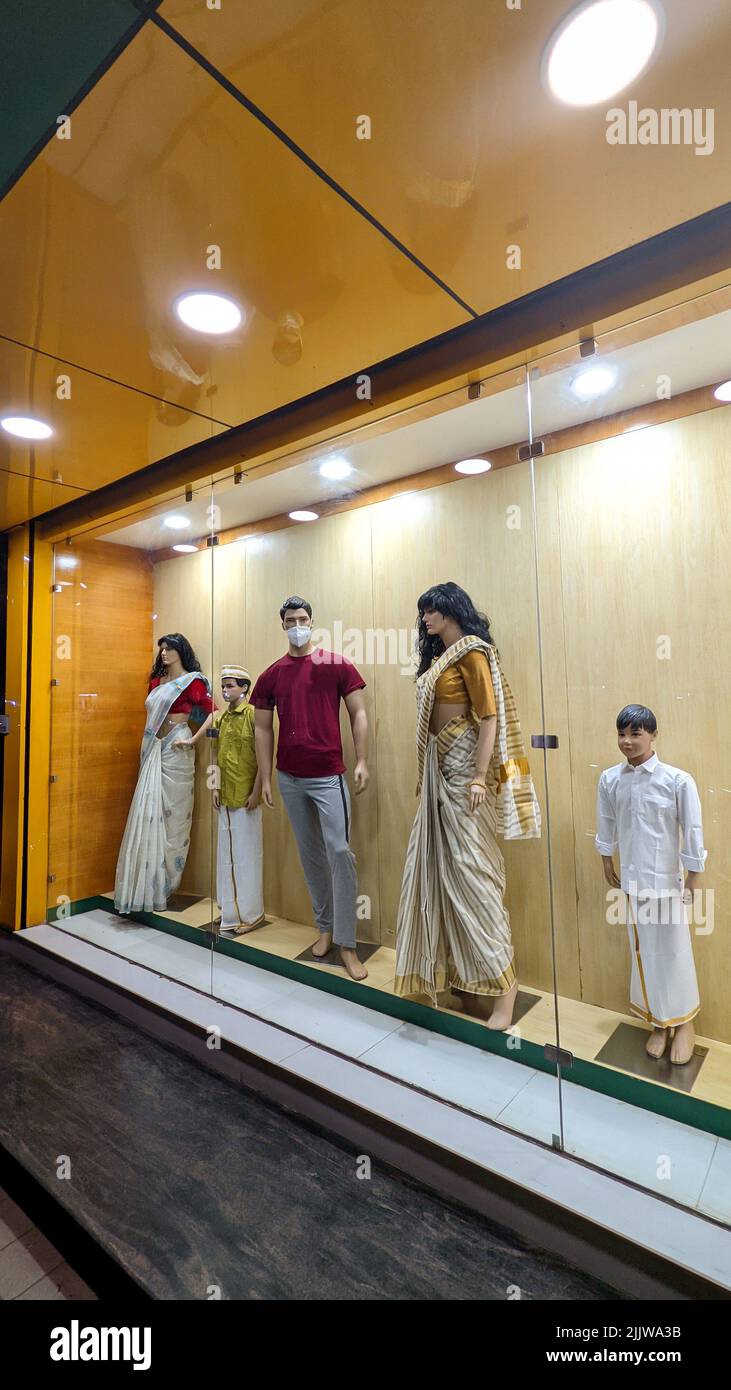 mannequins of adults and kids sizes, short and tall displayed inside a glass case in front of a clothing shop Stock Photo