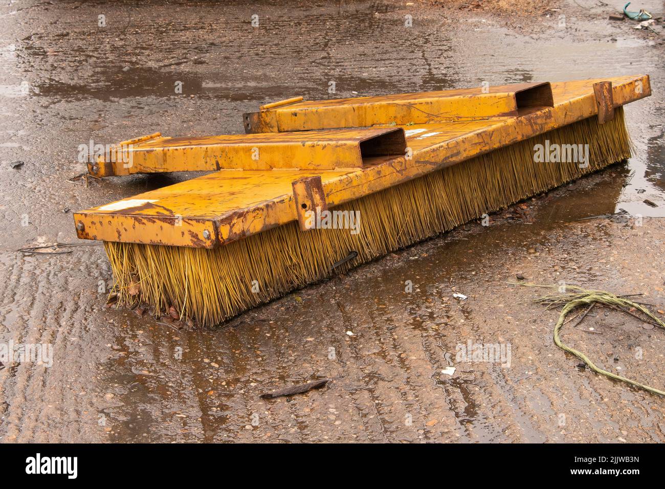 A yellow forklift road sweeper brush attachment part in rainy truck yard Stock Photo Alamy