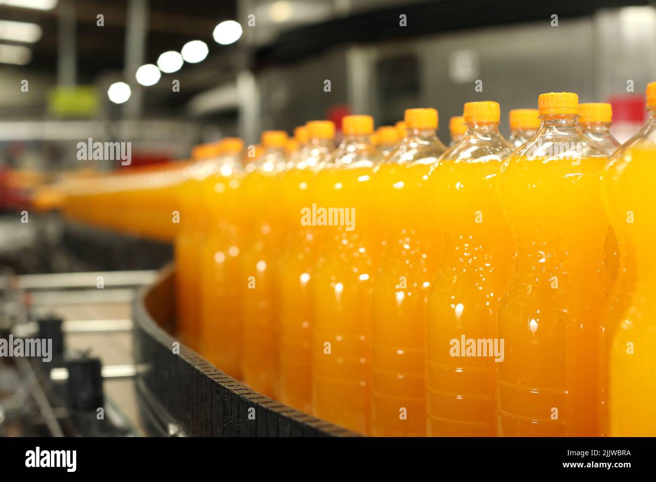 Production of carbonated drinks. Orange bottles on the production line Stock Photo