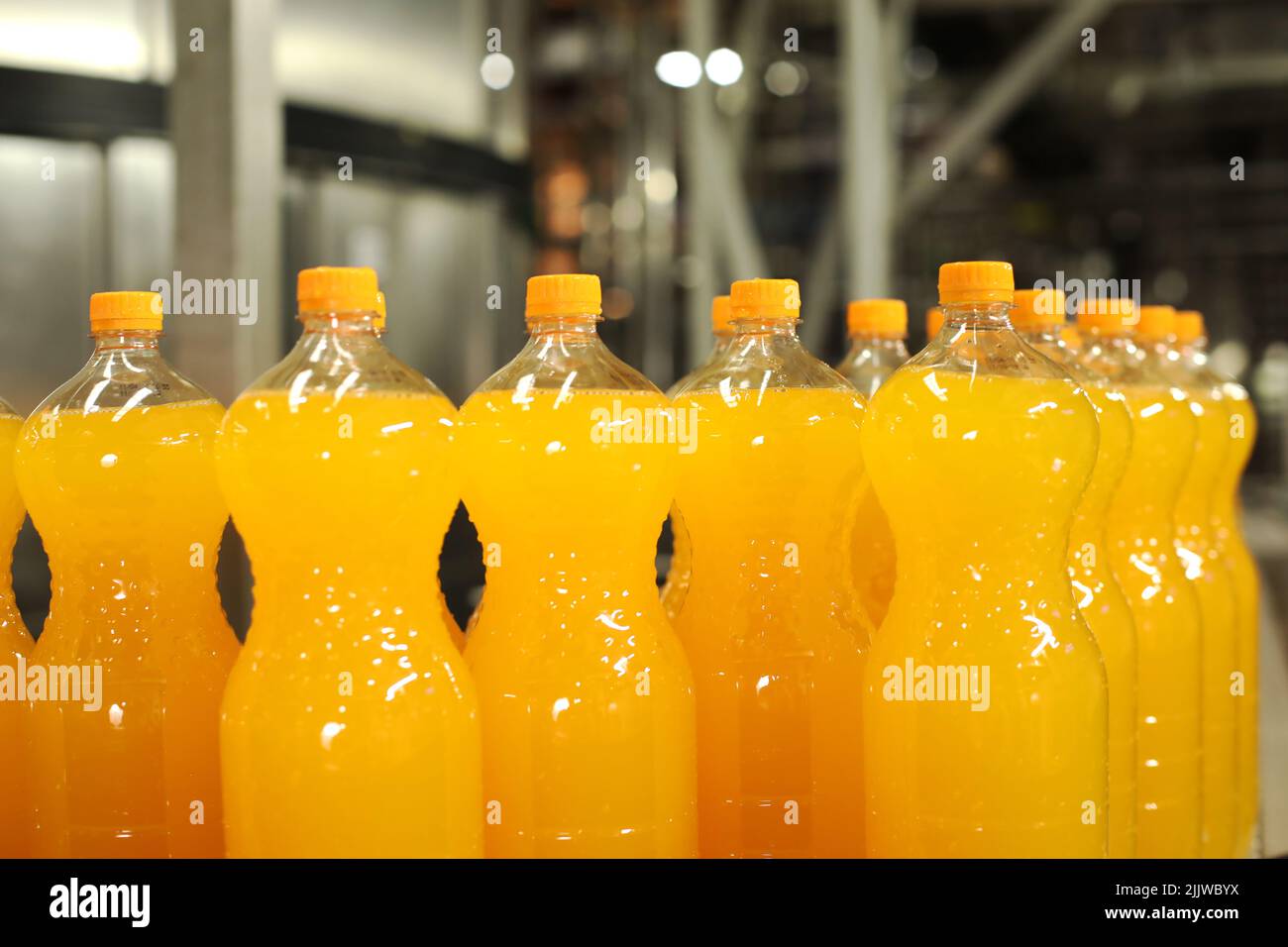 Production of carbonated drinks. Orange bottles on the production line