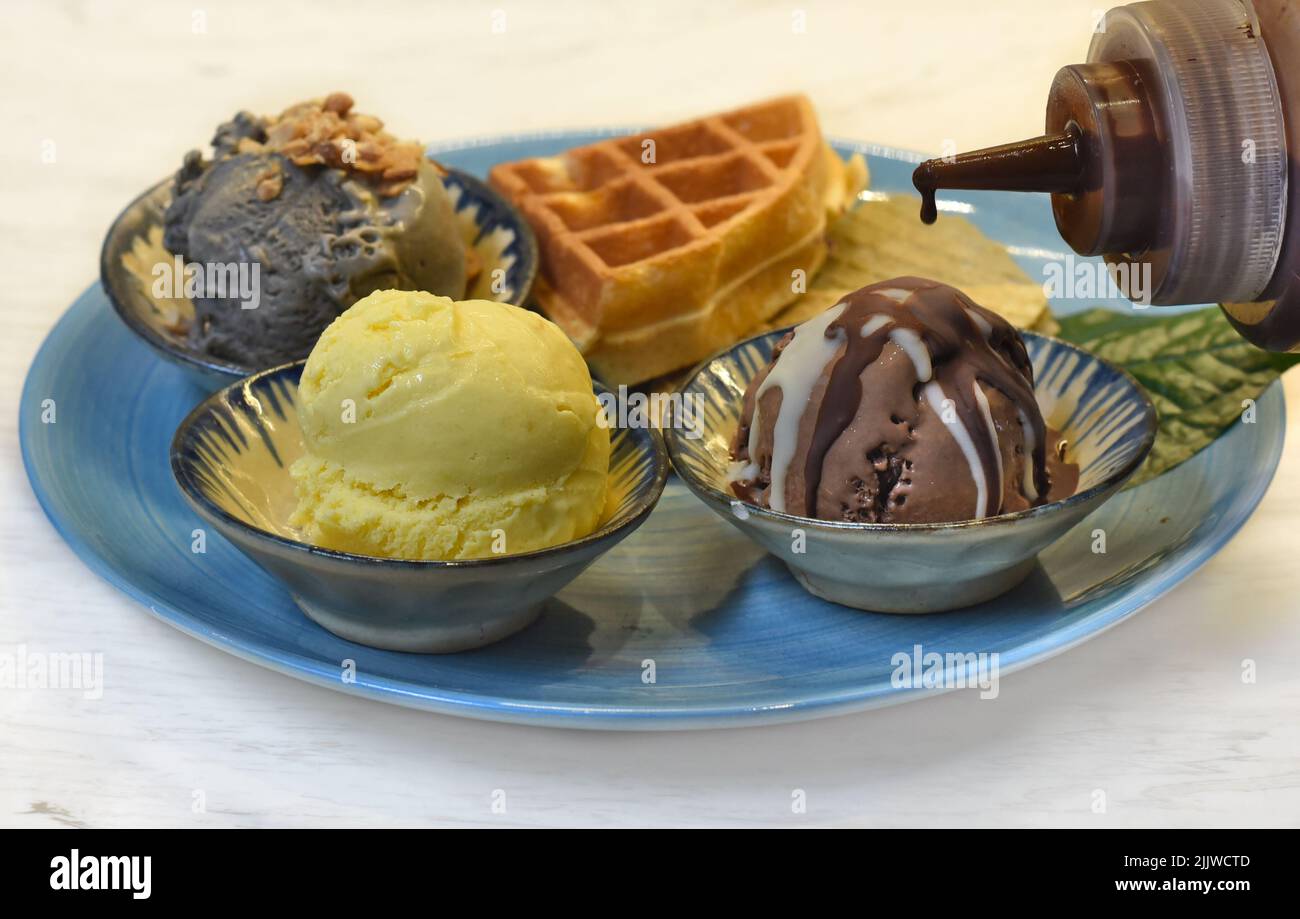 Homemade ice cream on blue plate with chocolate topping Stock Photo