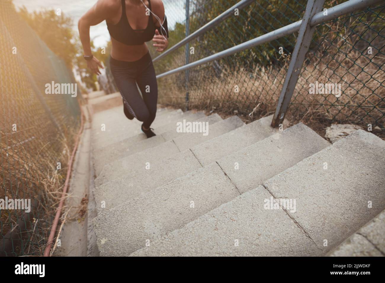 Fit young woman running up the stairs outdoors in the morning. Sporty young woman having a vigorous physical training. Stock Photo