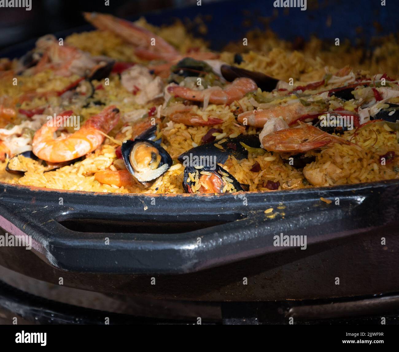 Traditional paella with seafood and chicken at food market in Paris