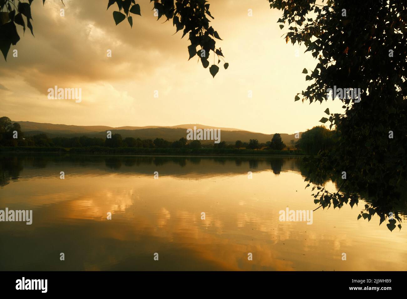 Golden sunset at the lake near Wernigerode in the Harz Mountains. Reflection of the clouds in the water Stock Photo