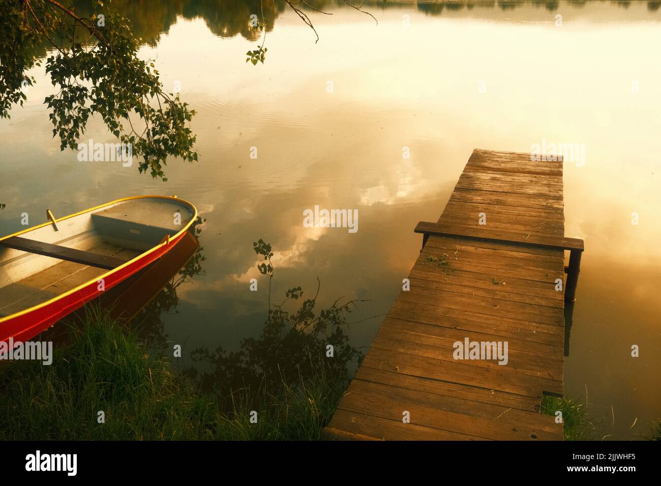 Romantic sunset at the lake with jetty and boat in town Wernigerode Stock Photo