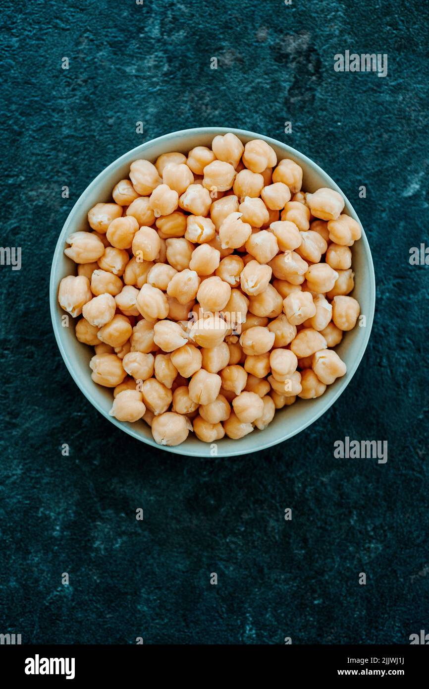 high angle view of some cooked chickpeas in a ceramic bowl placed on a dark stone surface Stock Photo