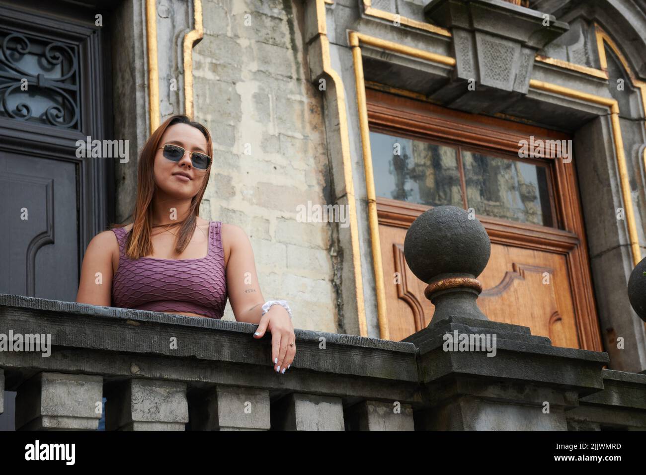 A  beautiful young female posing on a balcony of an old historical building in Brussels Stock Photo