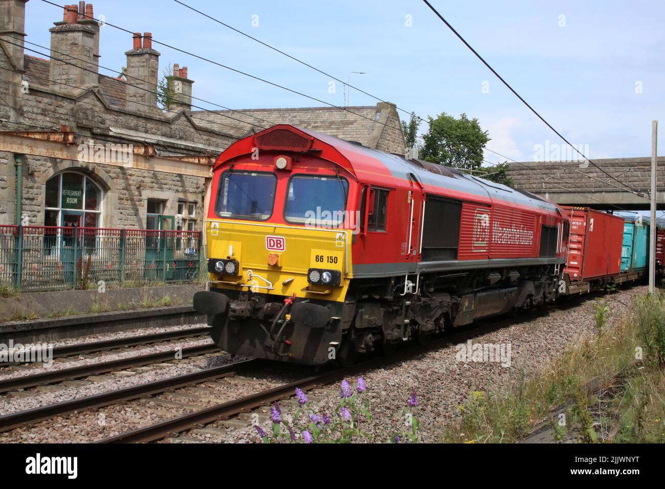DB Cargo UK class 66, 66150, heading south through Carnforth on the West Coast Main Line on Wednesday 27th July 2022 with a container train. Stock Photo