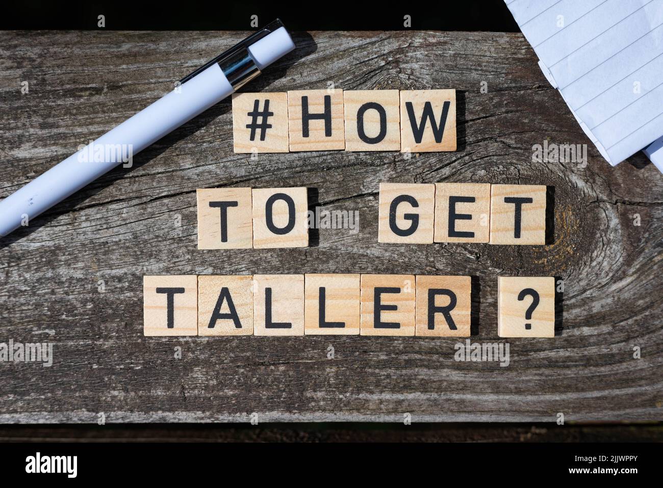 How to get taller question letters on wooden blocks on a wooden table with pencil and paper at the sides of the shot Stock Photo