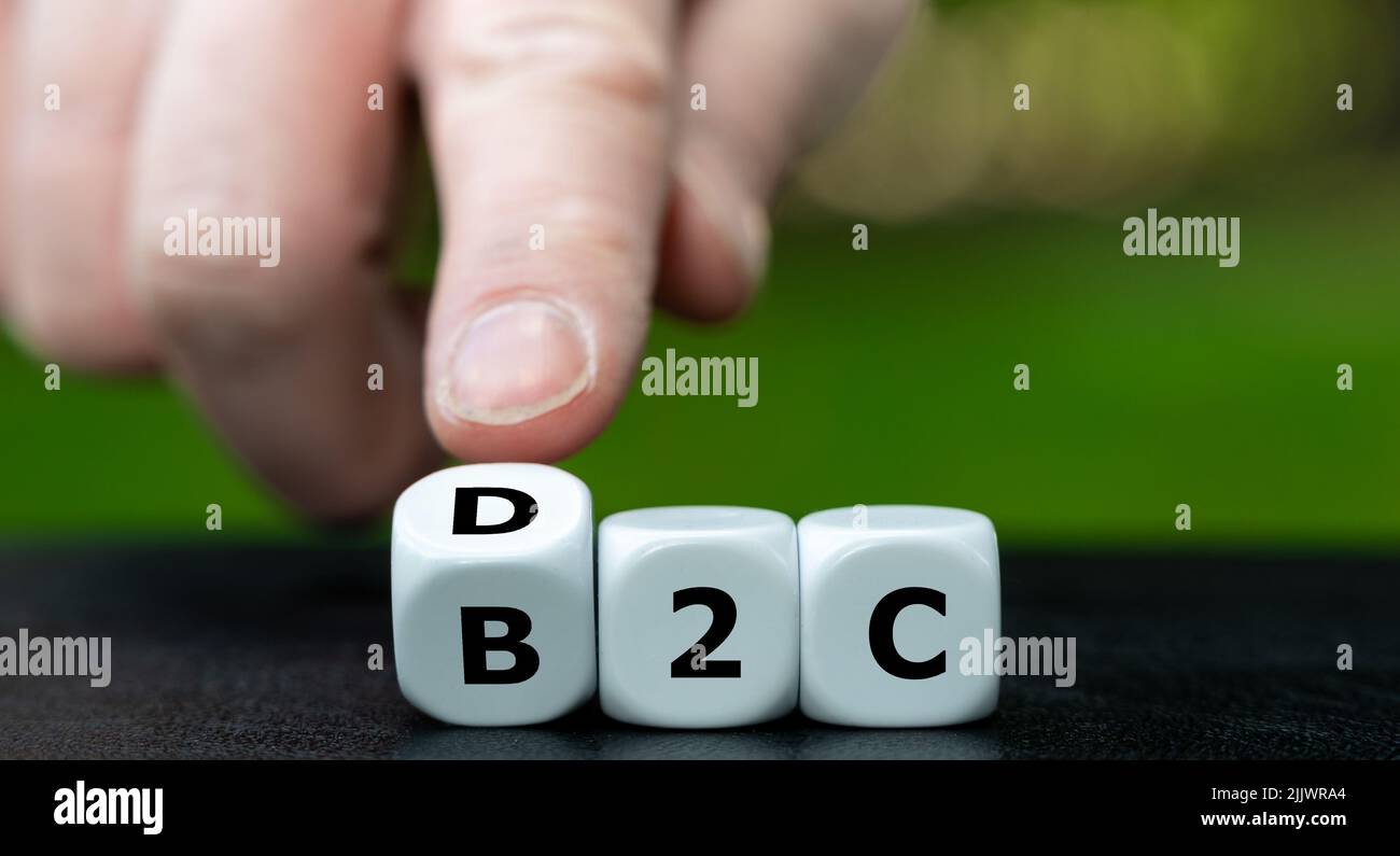 Hand turns dice and changes the expression 'business to consumer (b2c)' to 'direct to consumer (d2c)'. Stock Photo