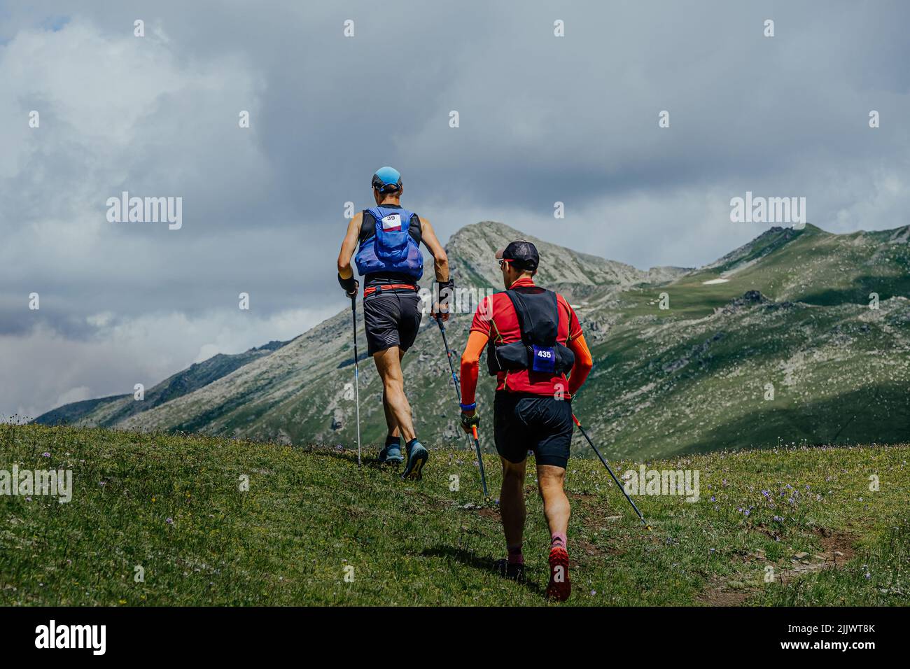 two athletes walk mountain trail during marathon Stock Photo