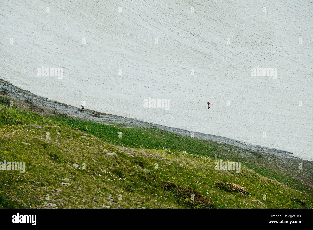 woman and man athletes run on snowy slope during marathon Stock Photo