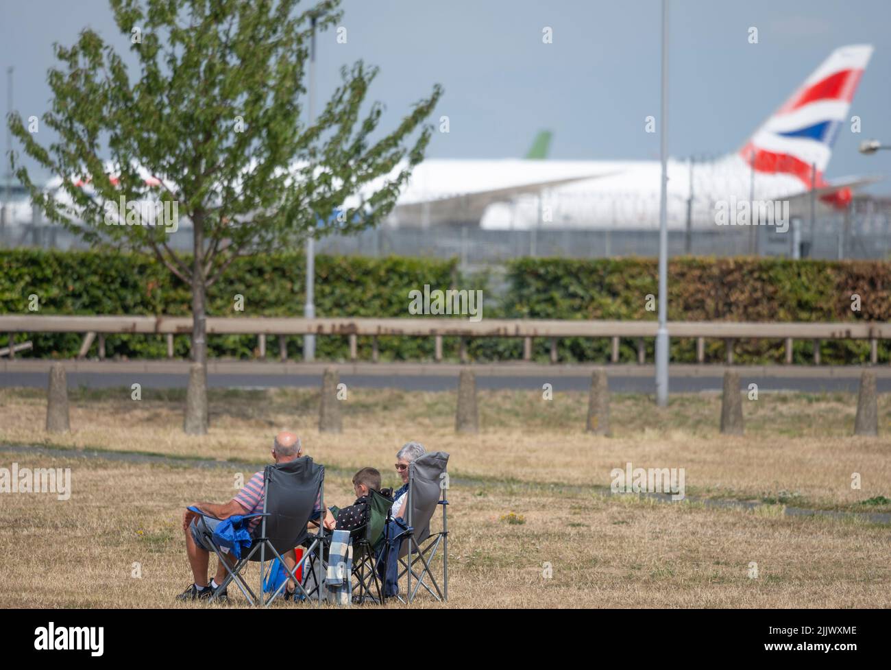 Heathrow Airport, London, UK. 28 July 2022. A family watching aircraft taking off from Southern runway at Heathrow on a hot summer day Stock Photo