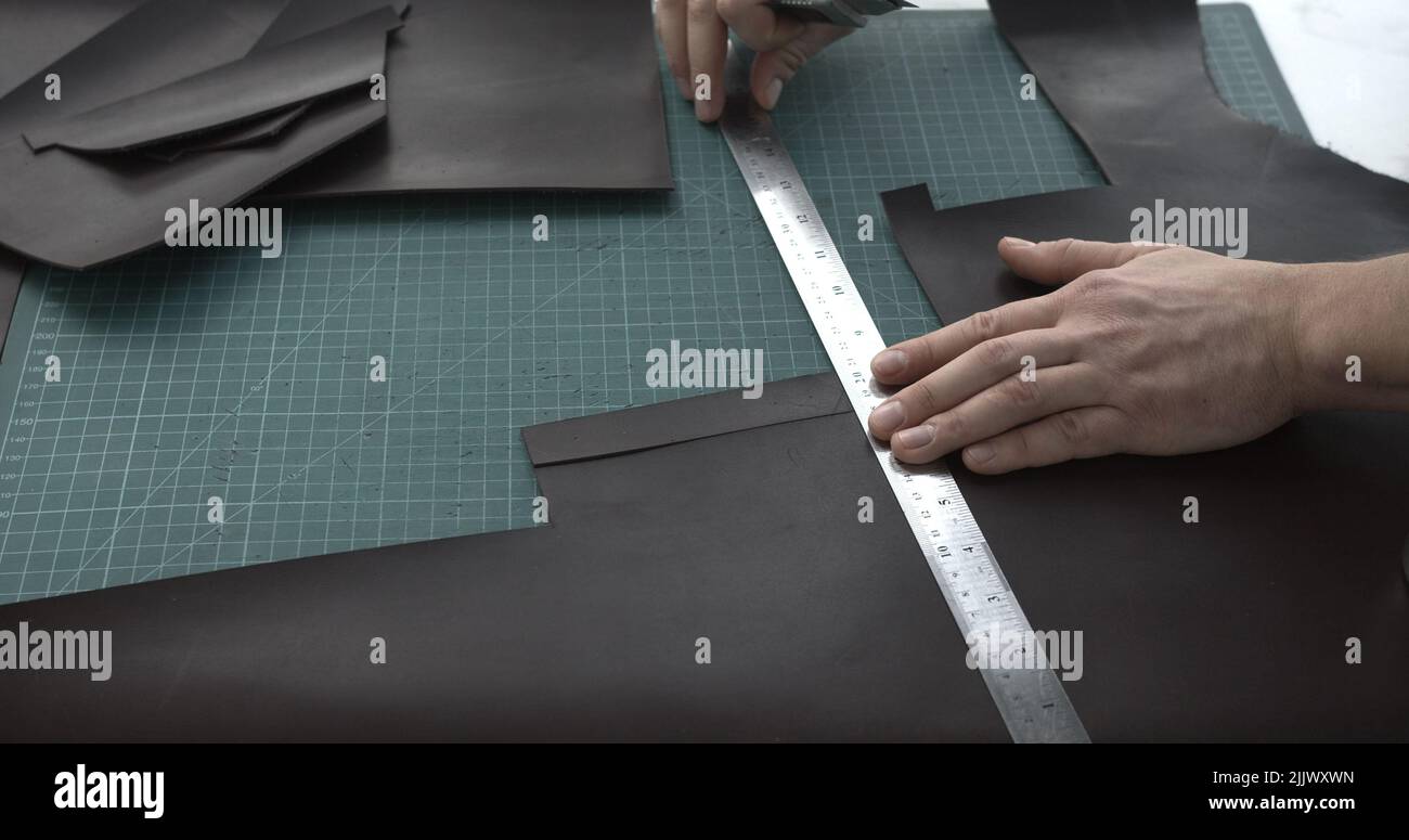 Top view leather craftsman working with brown natural leather work with ...