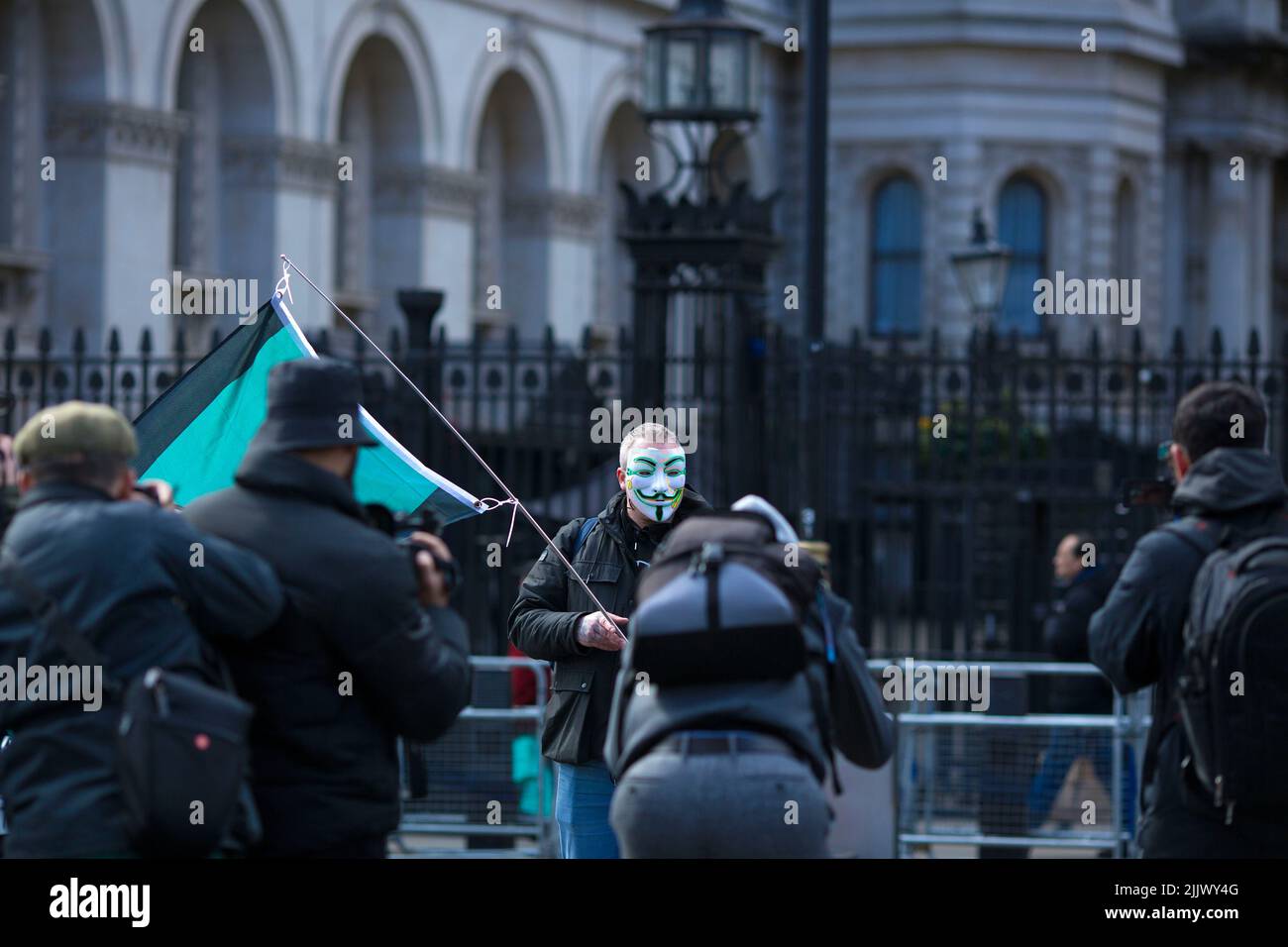 A person wearing a mask stands near the gates to Downing Street during a Cost of Living Crisis protest organised by the People’s Assembly in London. Stock Photo