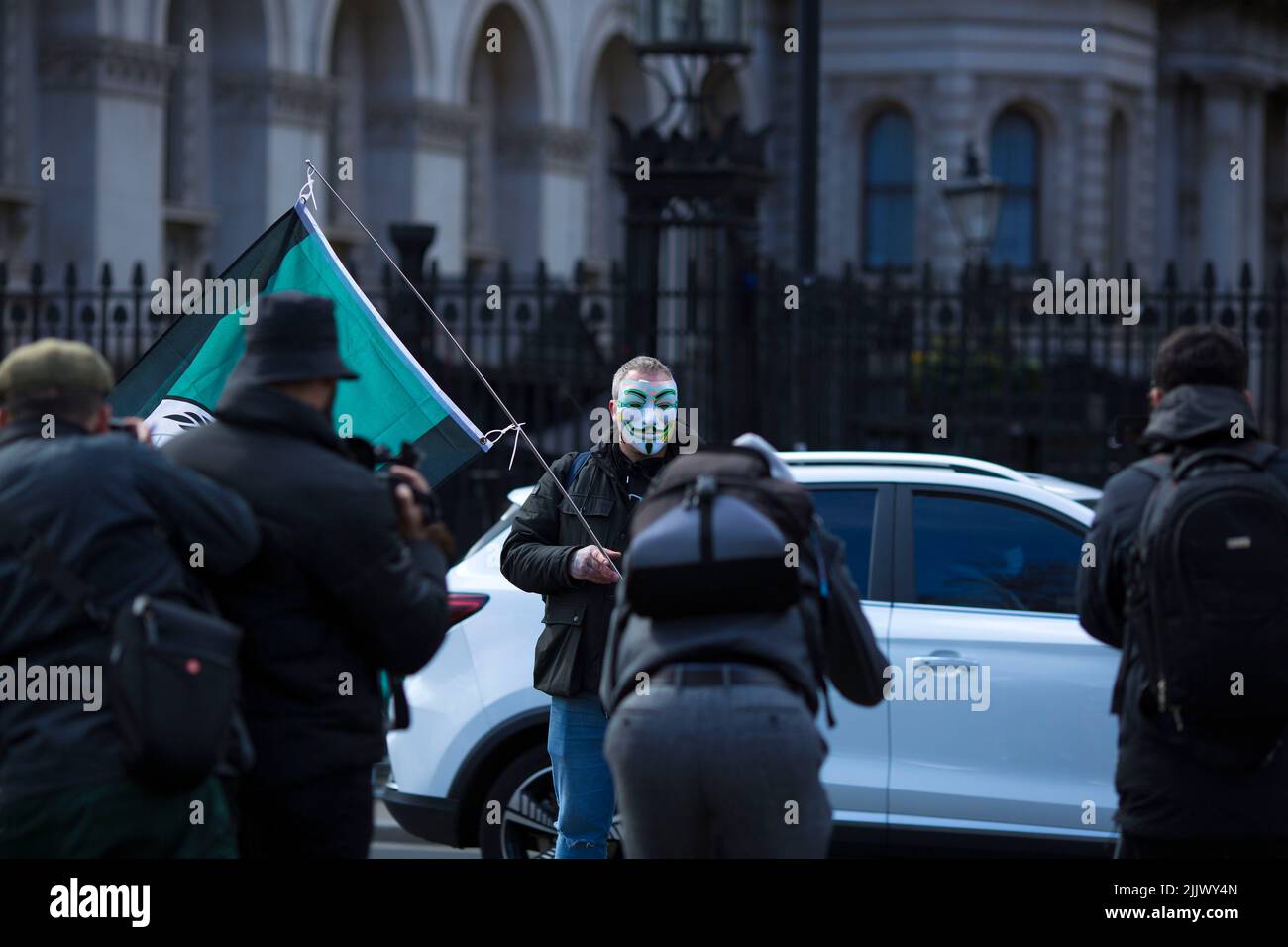 A person wearing a mask stands near the gates to Downing Street during a Cost of Living Crisis protest organised by the People’s Assembly in London. Stock Photo