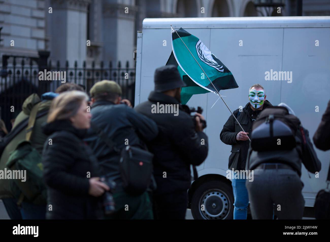 A person wearing a mask stands near the gates to Downing Street during a Cost of Living Crisis protest organised by the People’s Assembly in London. Stock Photo