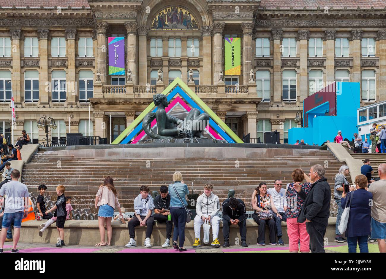 Visitors to Birmingham city centre sitting in front of The Floozie in the Jacuzzi and the Birmingham City Council House. Stock Photo