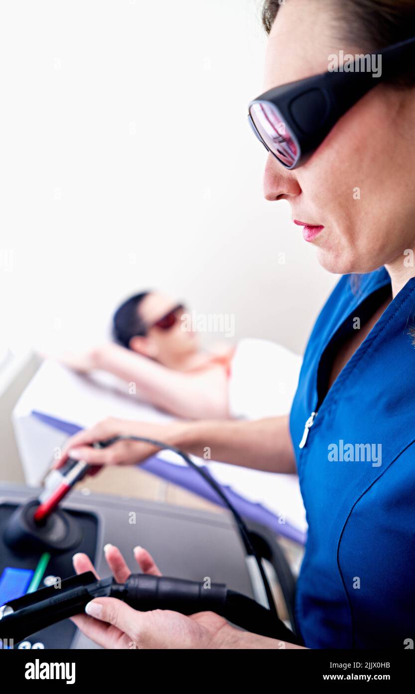 Female esthetician in protective goggles controlling laser epilation