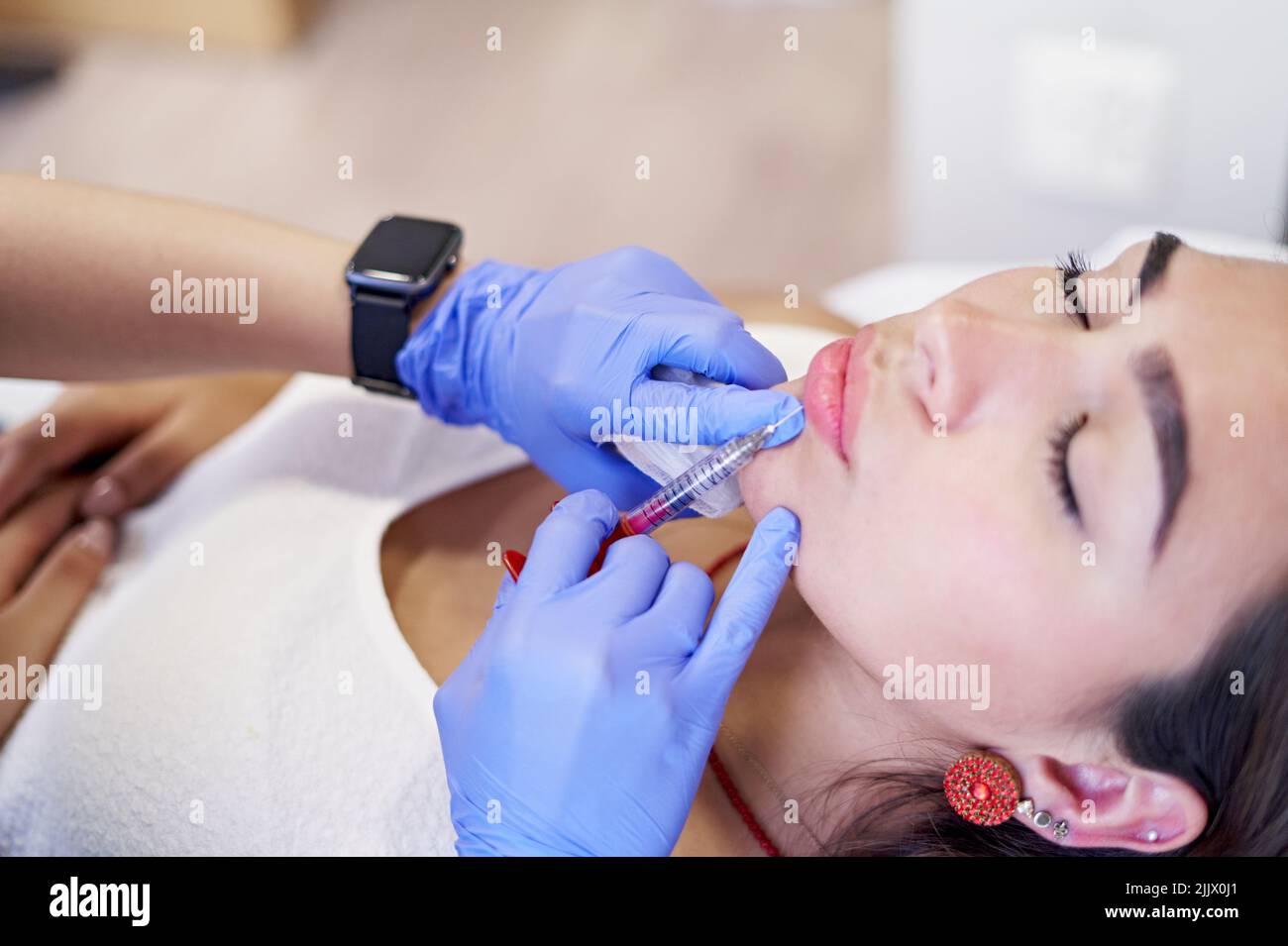 From above crop unrecognizable esthetician in latex gloves injecting ...