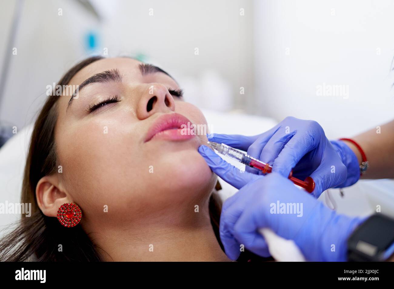 From above crop unrecognizable esthetician in latex gloves injecting ...