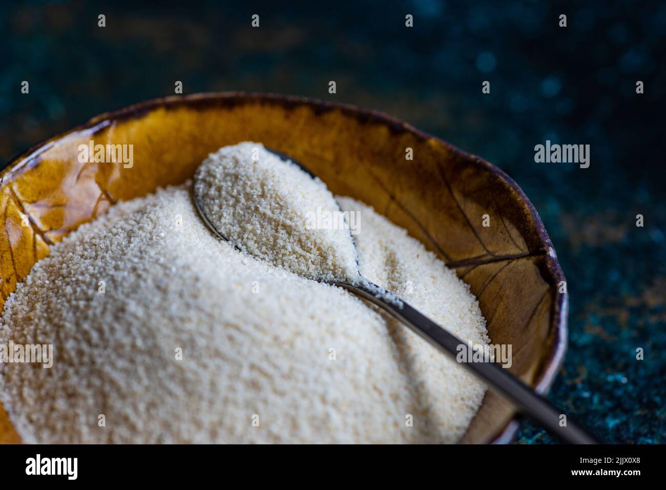Organic corn flour in the ceramic bowl on stone table Stock Photo