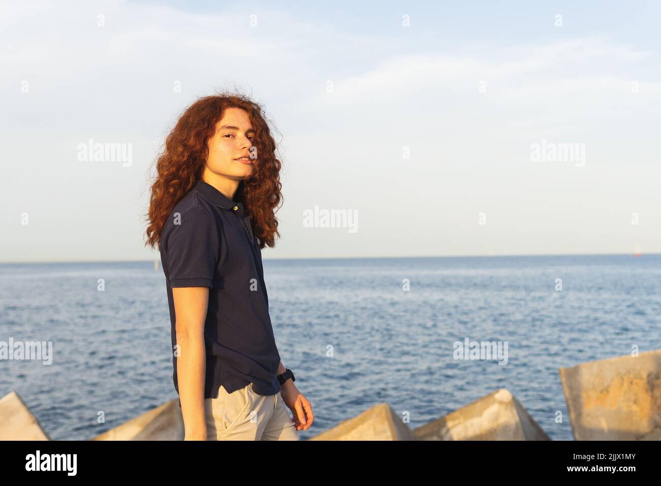 Portrait of young Woman with red hair standing at beach against sky Stock Photo