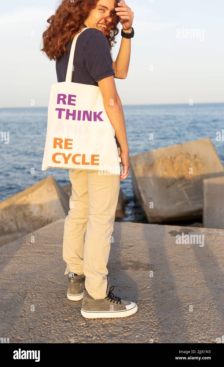 Side view of young Woman carrying shoulder bag with rethink and recycle