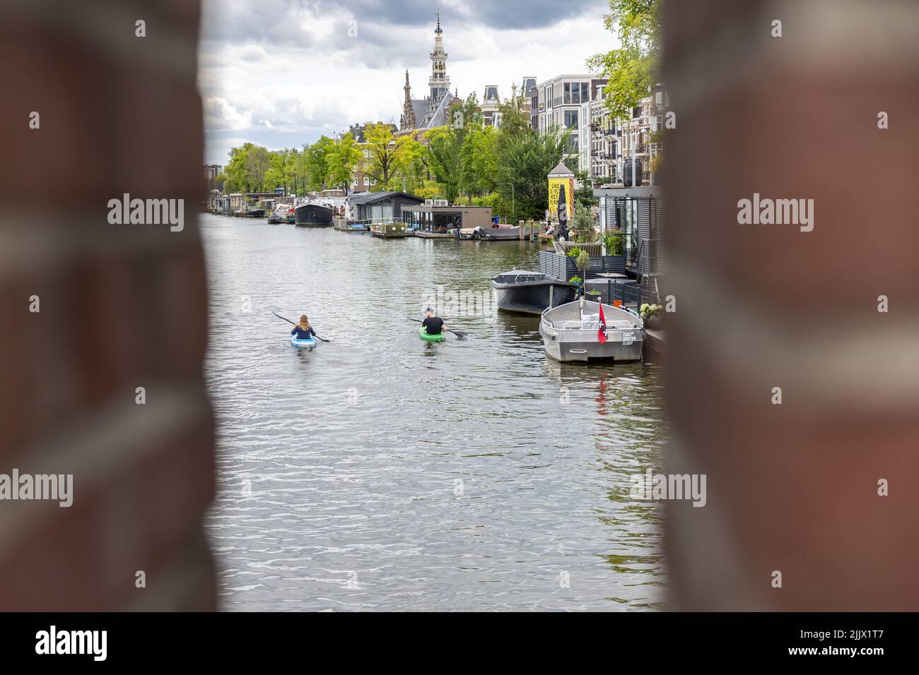 20220727 143640 AMSTERDAM People on a sup board row across the Amstel, near the Royal 20220727 143640 AMSTERDAM People on a sup board row across the Amstel, near the Royal