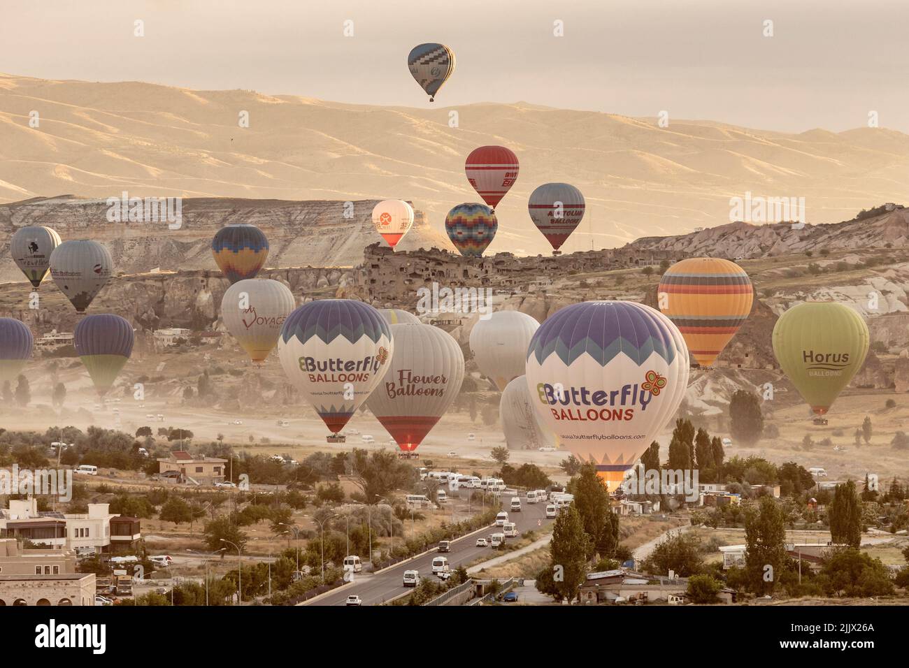 GOREME/TURKEY - June 27, 2022: colorful hot air balloons take flight over the city of goreme at sunrise. Stock Photo