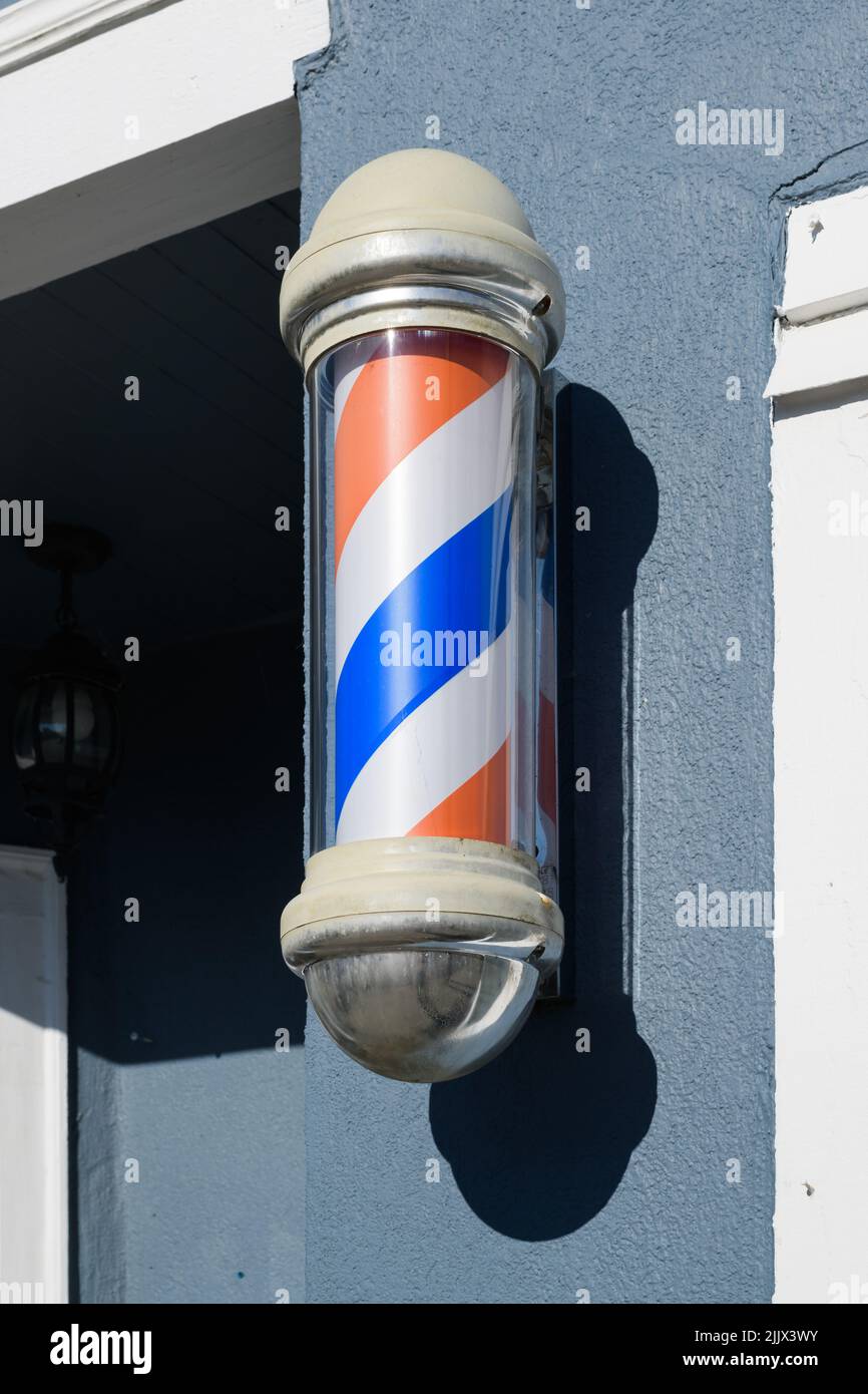 Striped barber pole in glass mounted on a wall with shadow Stock Photo