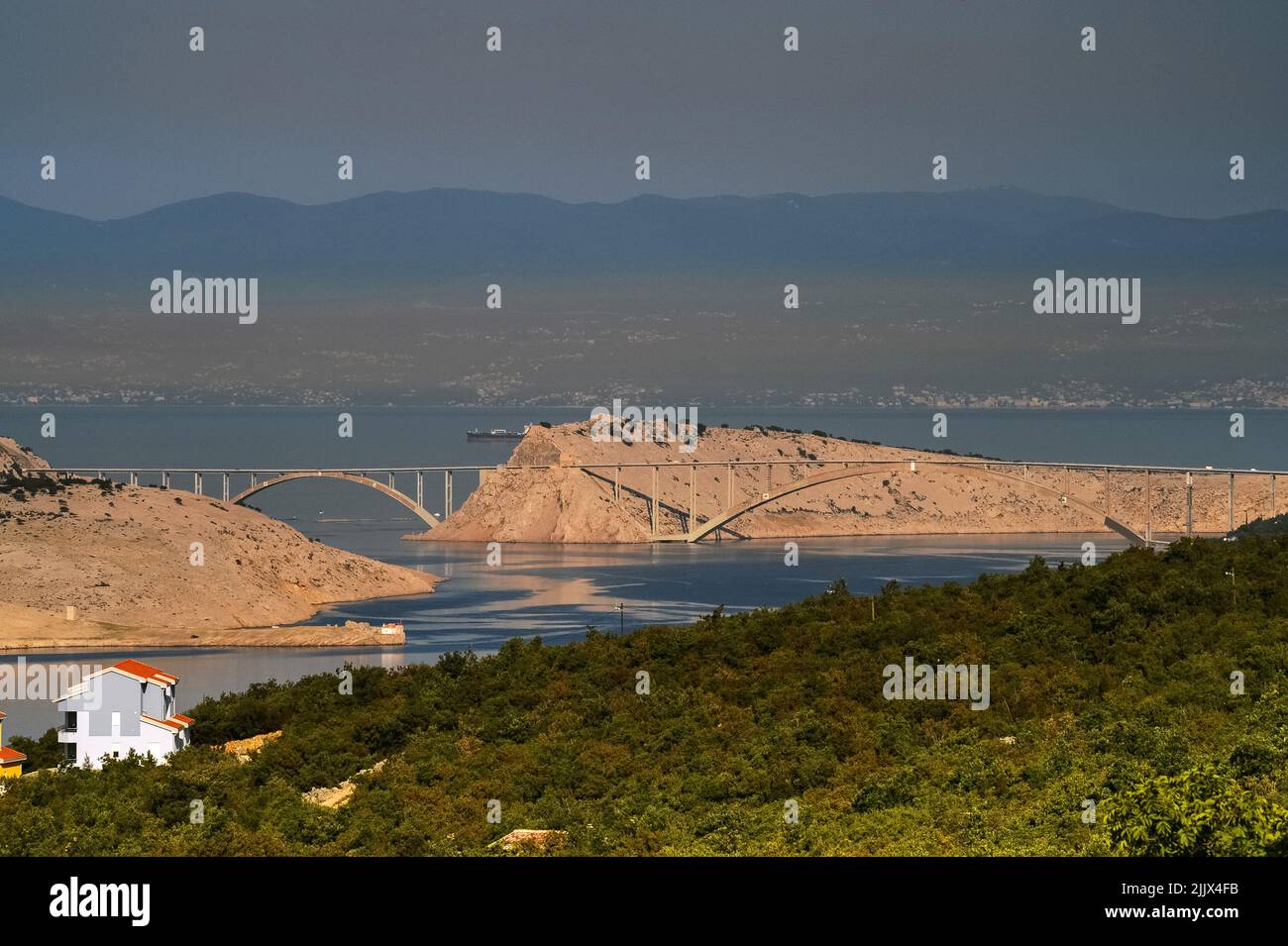 Layers of atmospheric pollution hanging in sunshine and still air - in September 2007 - above Krk Bridge, the 1.4 km concrete crossing linking Krk Island, in the northern Adriatic Sea's Bay of Kvarner to the mainland of Croatia near the large seaport and shipbuilding centre of Rijeka, the city's international airport and the oil refinery at Omišalj. Stock Photo