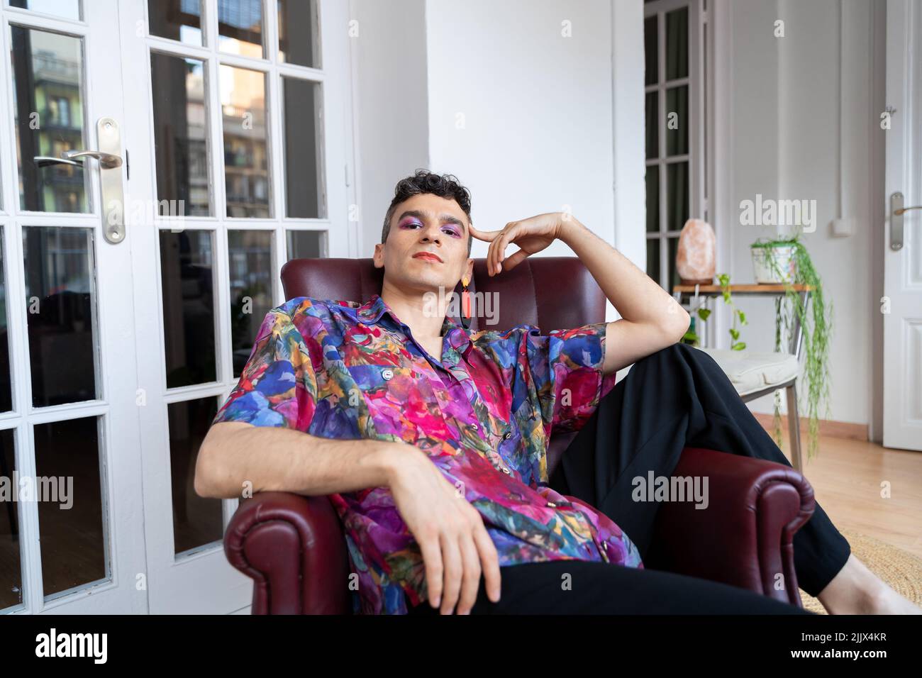 Portrait of confident transgender man in casual sitting on armchair at