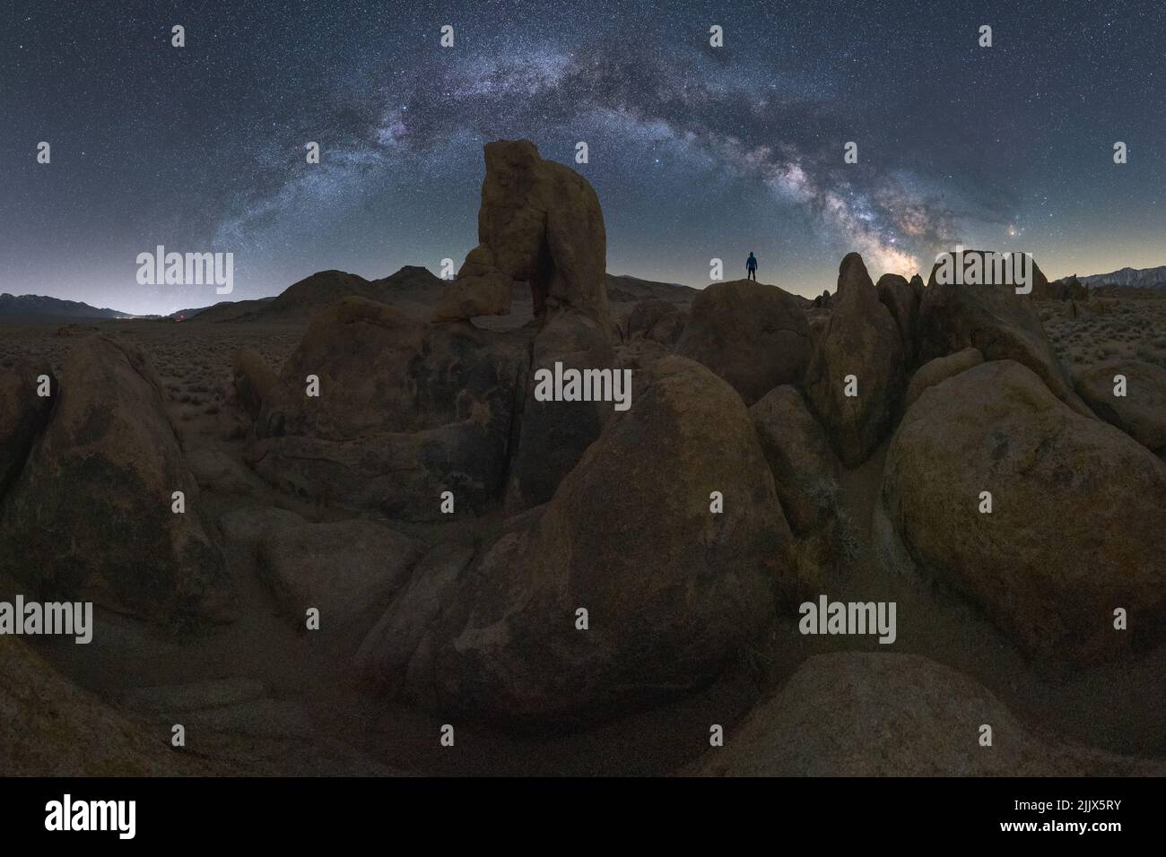 Anonymous explorer standing on rock in highlands against night starry ...