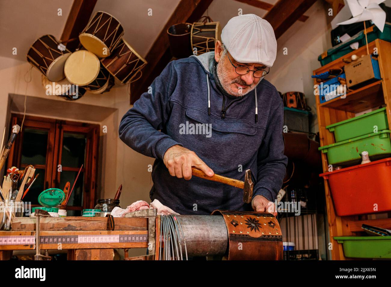Professional male master using hammer while making shell of drum with creative patterns while working in light workshop with special instruments Stock Photo