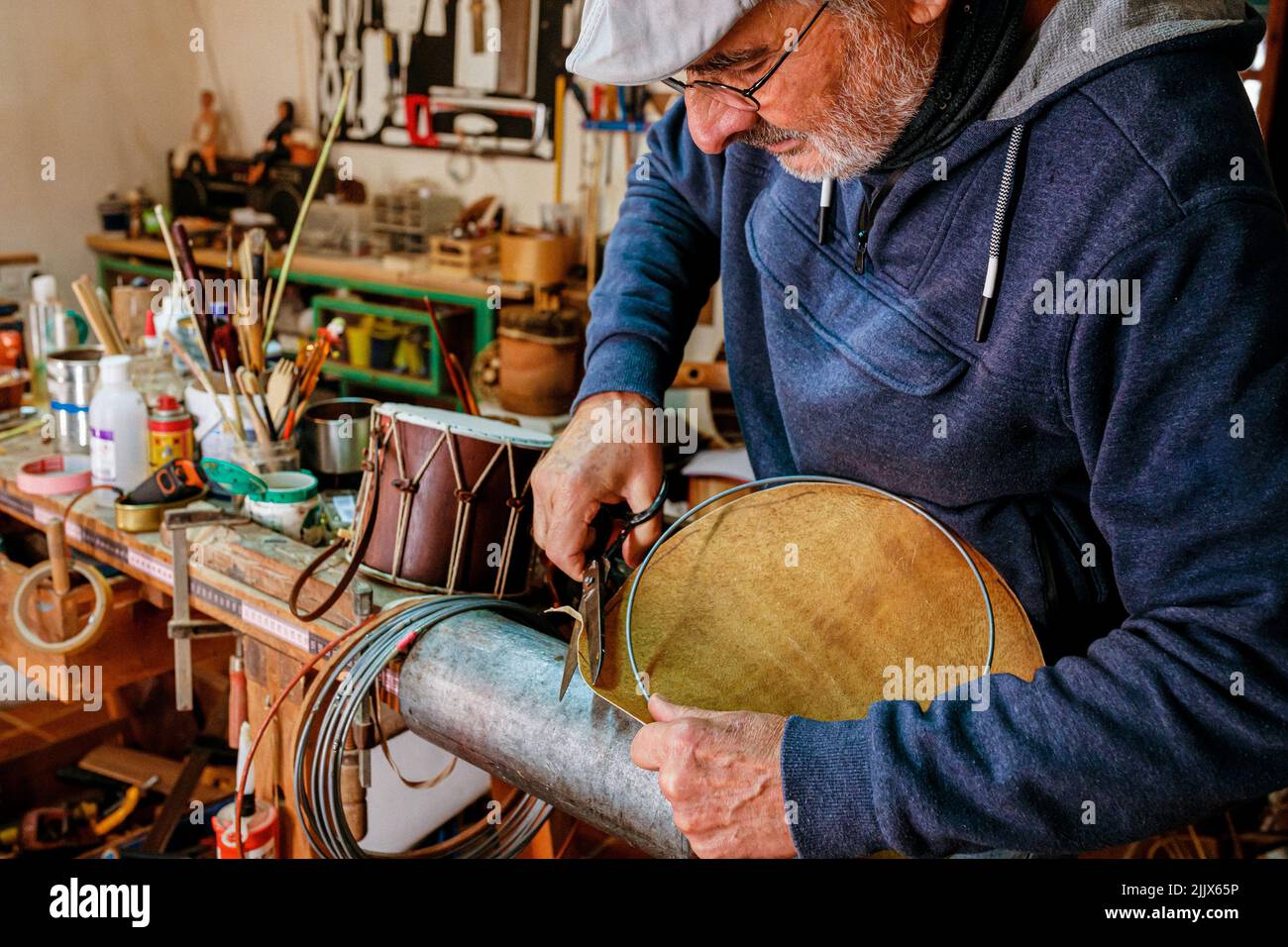 Male artisan using scissors while cutting off metal bearing edges of