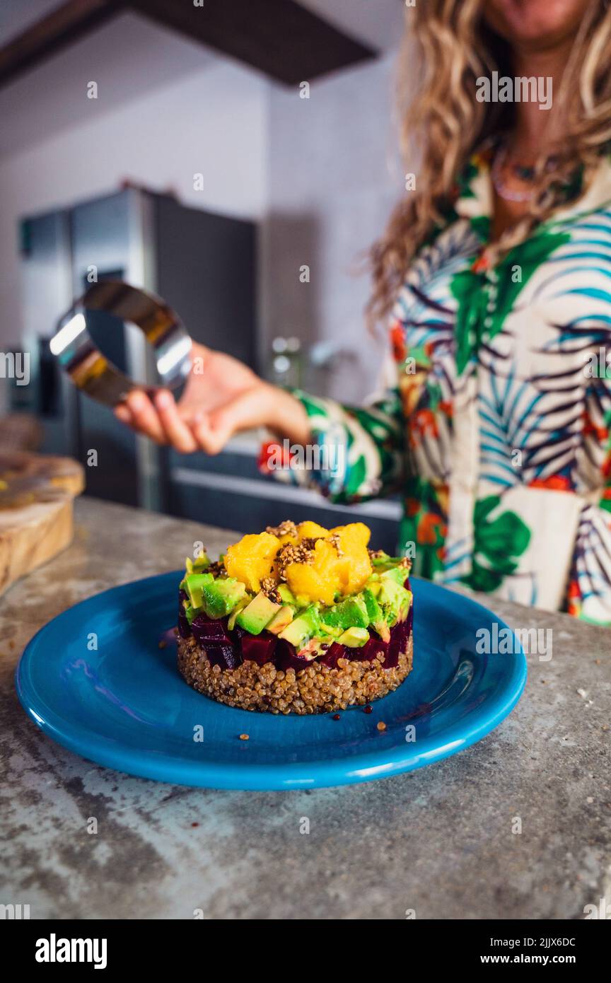 Soft focus of delicious layer salad made of quinoa and beet with avocado and mango and served on plate in kitchen at home Stock Photo