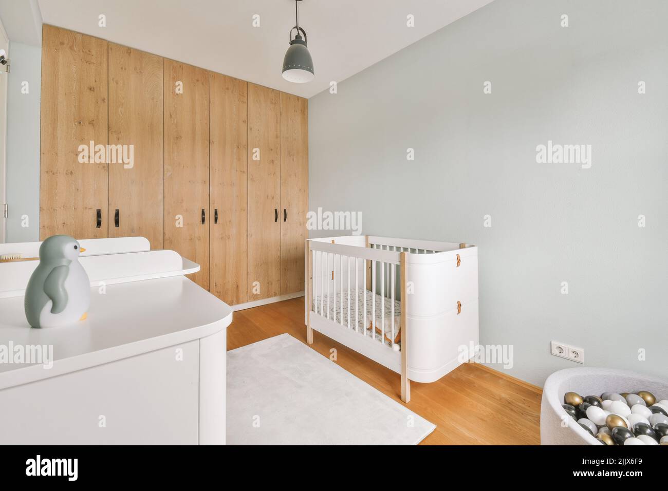 Interior of white room with baby crib and commode near window in