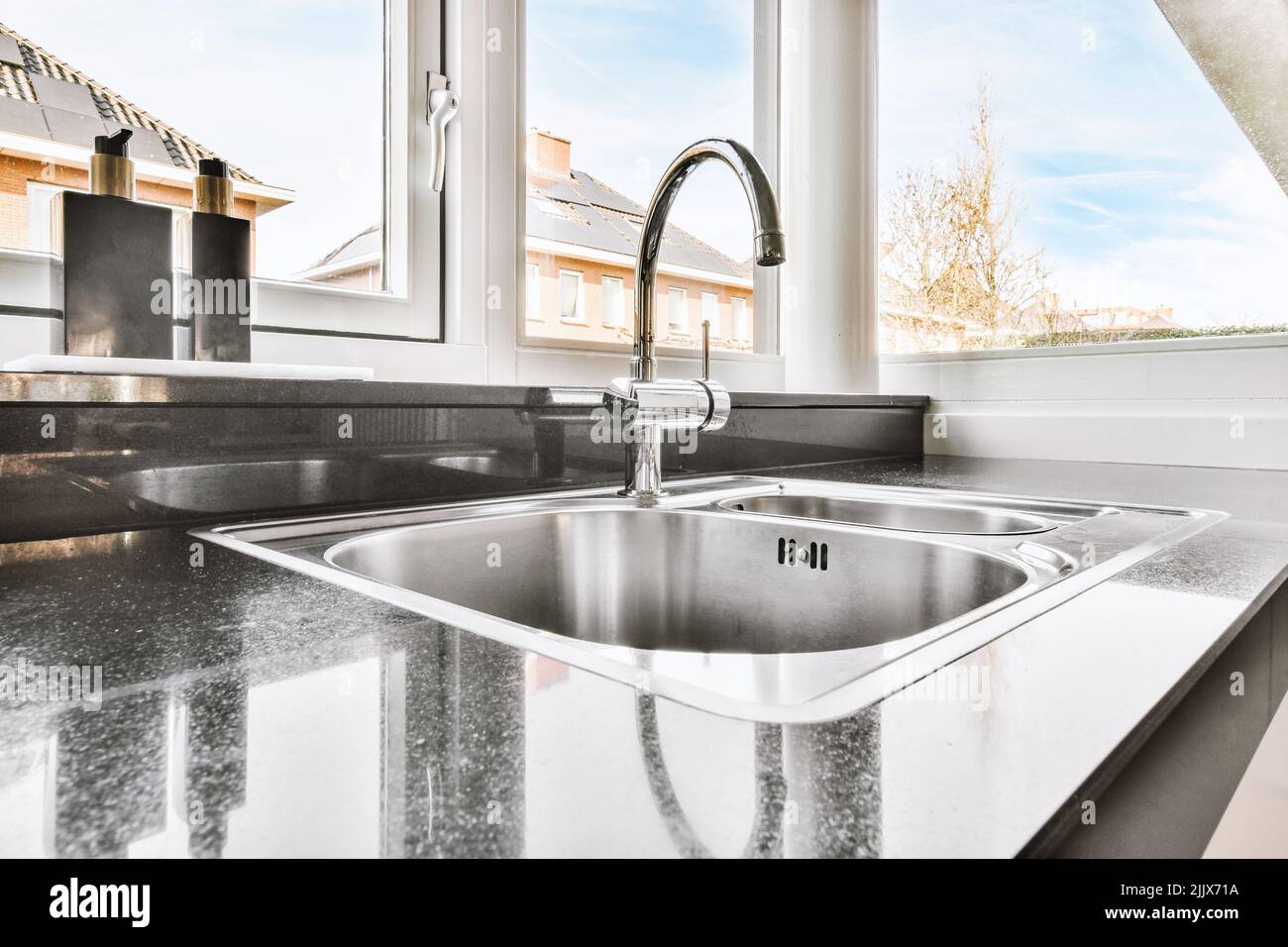 Detail of a kitchen sink of a modern house next to a bright window ...