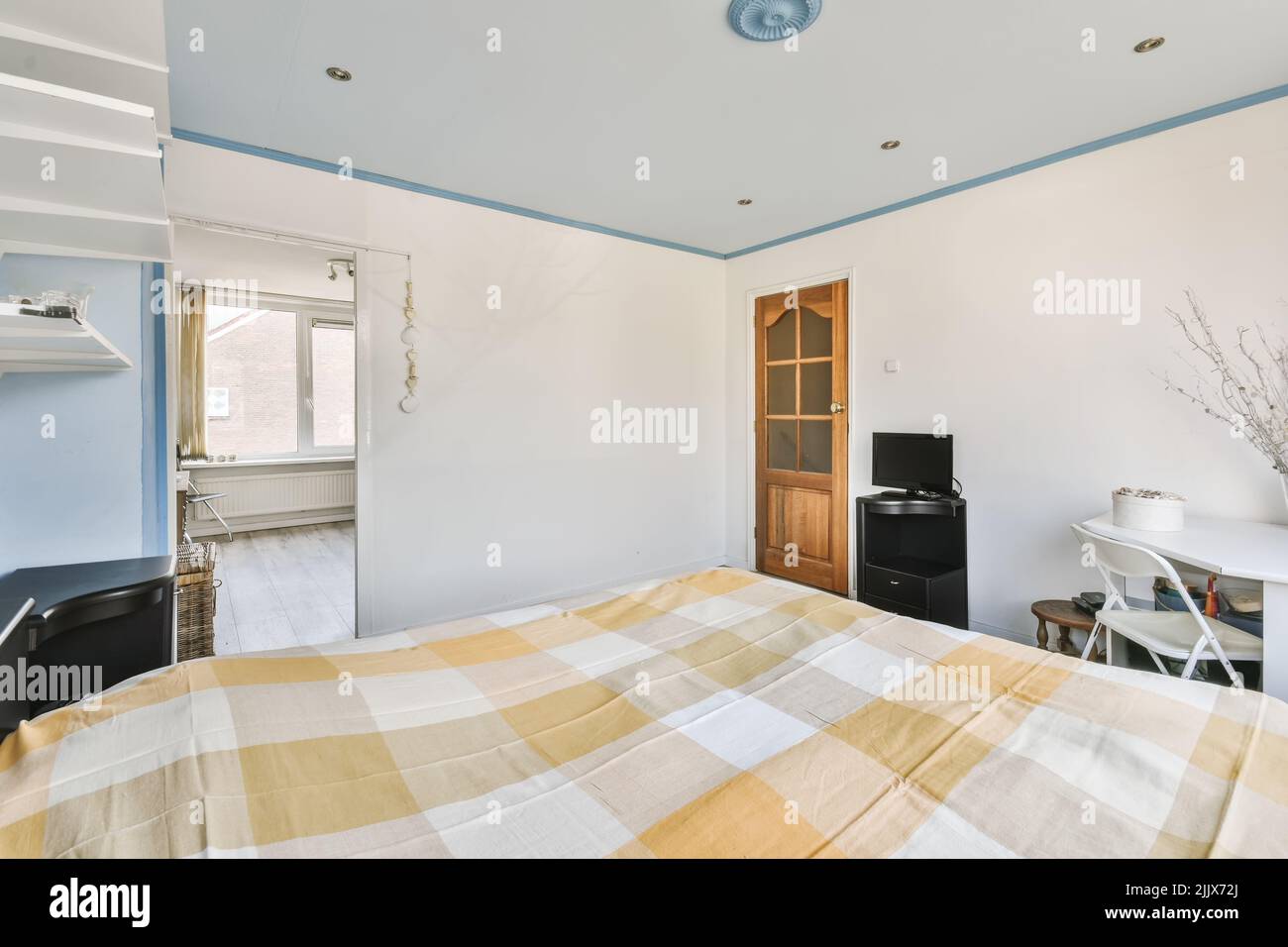 Table desk with modern tv placed in light spacious bedroom with blue
