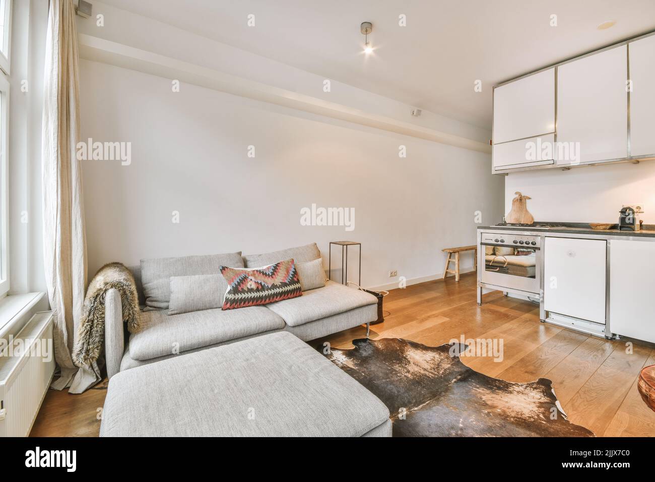 Comfortable sofa located in living room with open plan kitchen in