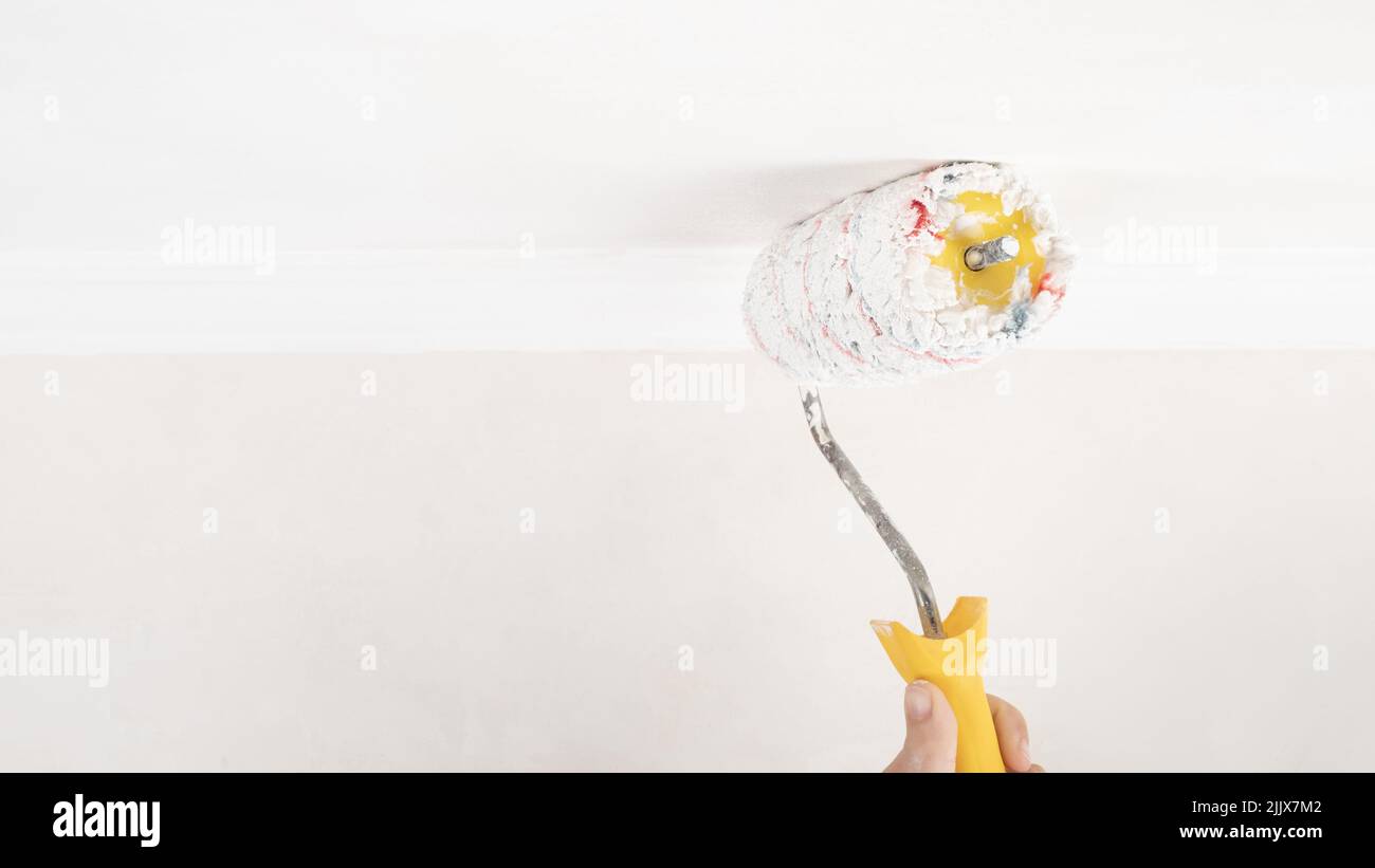 painting a white ceiling with a roller, home renovation. Stock Photo