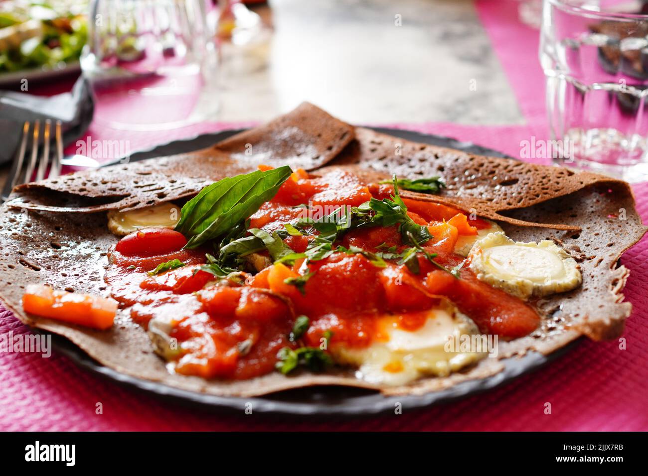 French buckwheat crepe Galette with fresh tomato and goat cheese, basil at creperie in France Stock Photo