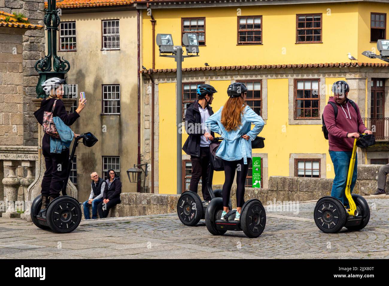 Group of tourists using Segway personal transporter scooters whilst sightseeing in the centre of Porto a major city in northern Portugal. Stock Photo