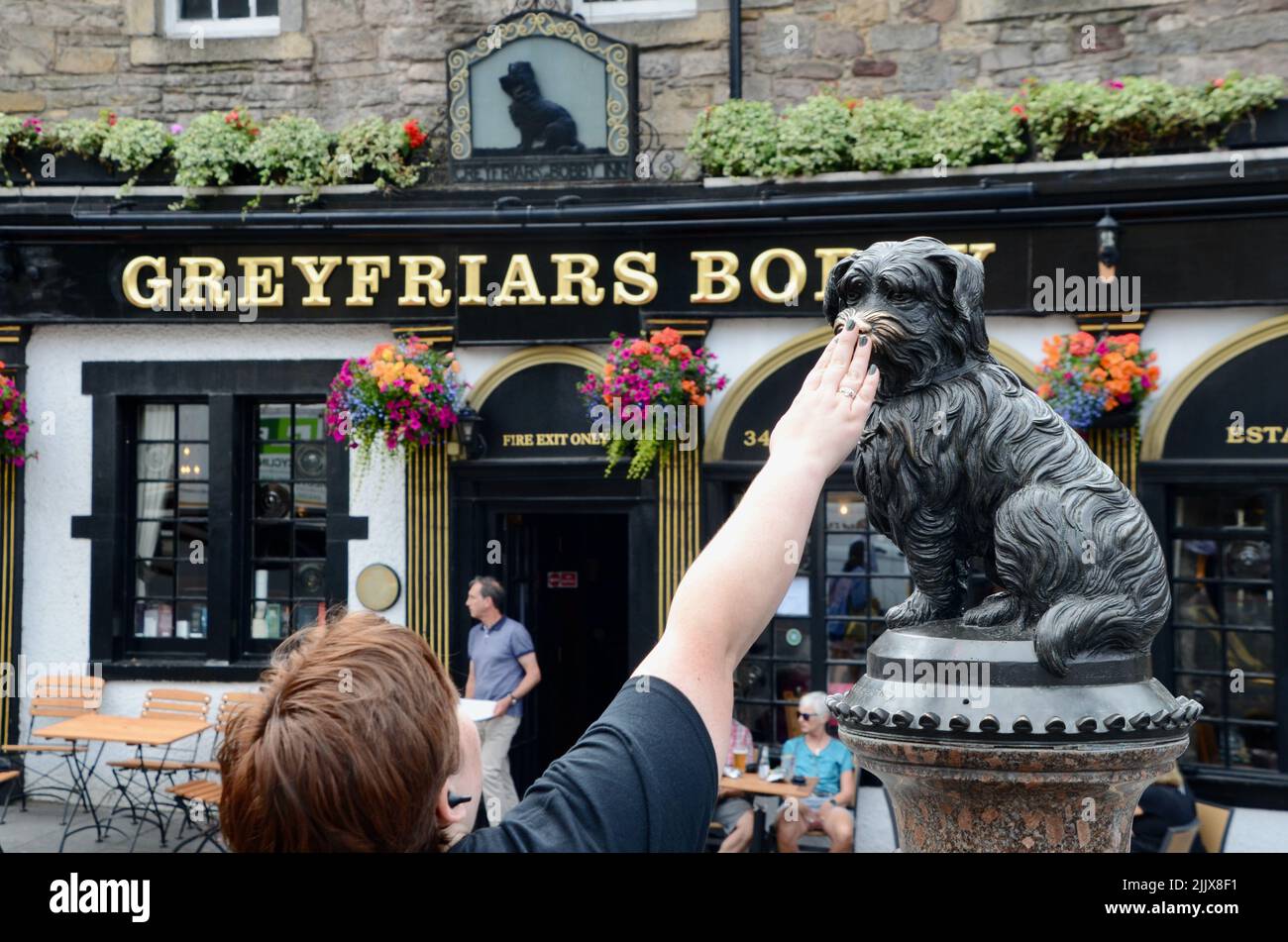 tourists with the greyfriars bobby statue touching his nose for luck edinburgh royal mile scotland in summer 2022 UK Stock Photo