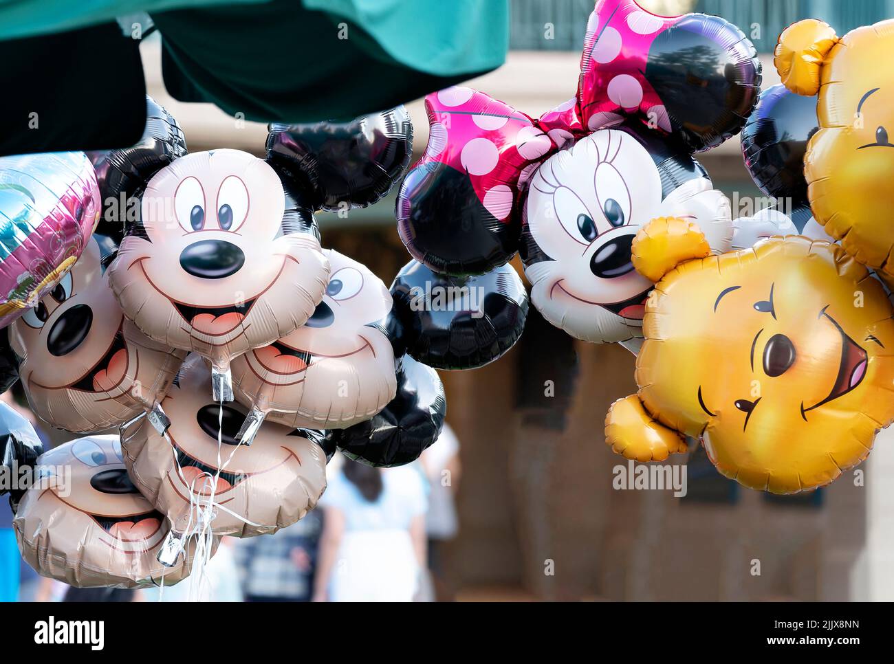A group of inflated Micky Mouse, Minnie Mouse and Pooh bear foil  character helium balloons clustered together and floating facing the camera Stock Photo