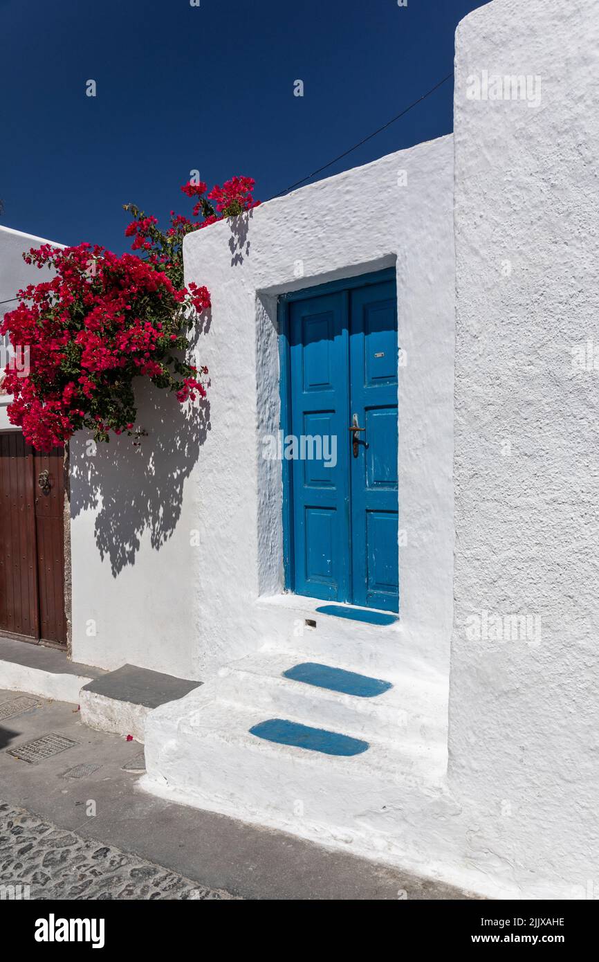 Tradition Greek blue door, whitewashed building with red flowers against a blue sky, Megalochori village, Santorini, Cyclades islands, Greece, Europe Stock Photo