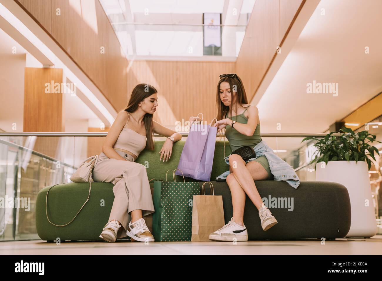 Two beautiful best friends at the mall looking at the bags while