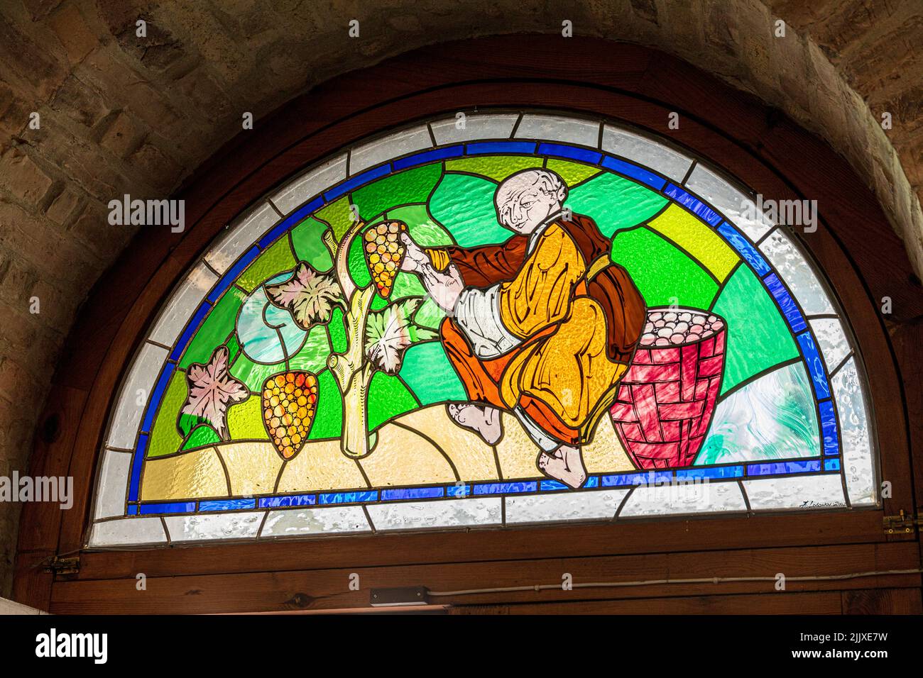 A stained glass window of a monk harvesting grapes in a shop in the Old Town of Tallinn the capital city of Estonia Stock Photo