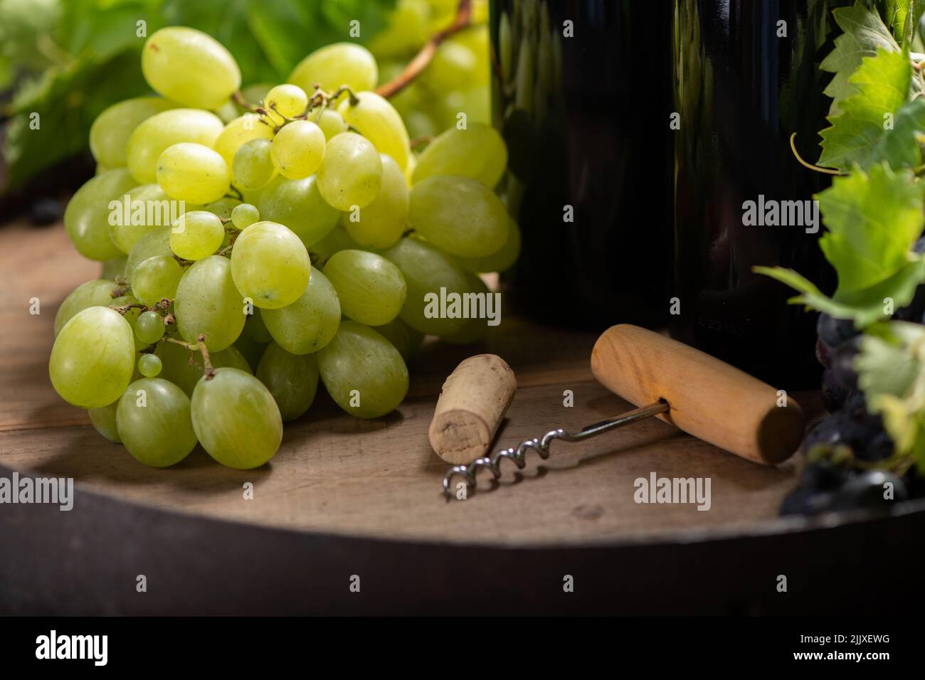 A wine stopper with a corkscrew on a wooden table in the background two bottles of wine. Close up Stock Photo